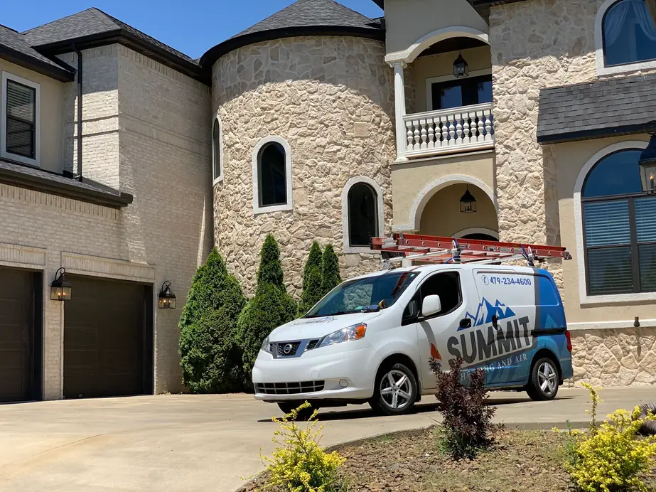 A Summit Heating and Air van parked in the drive of a stone and brick home in Northwest Arkansas