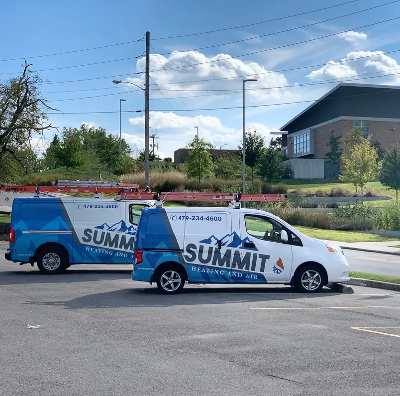 Two Summit Heating and Air vans with ladders on the racks, parked side by side